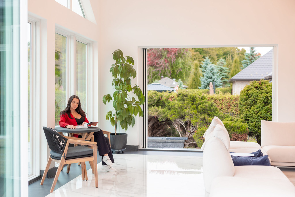 Bright, clean modern living room with large windows overlooking a lush garden — the kind of space Elevation Pro Services maintains